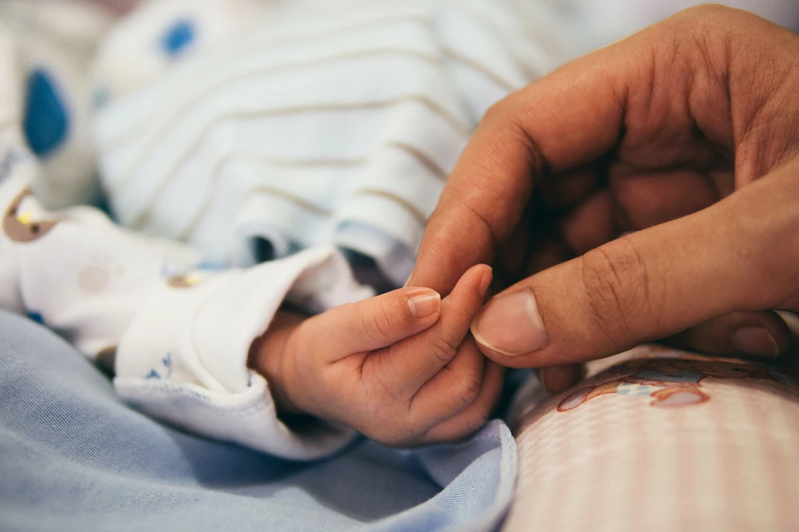Die Hand eines Babys wird von der Hand der Mutter gehalten.